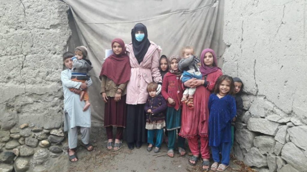 An Afghan woman, eight children, and two babies stand together in a group