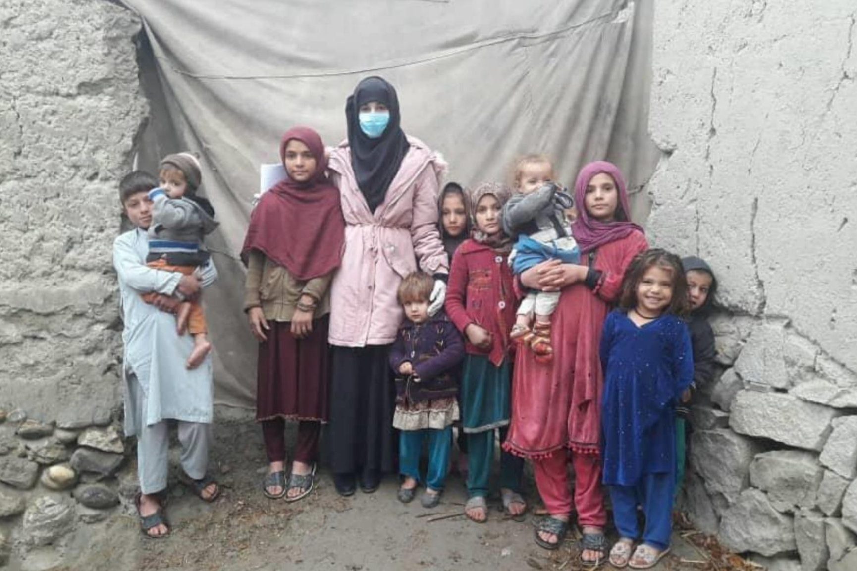 An Afghan woman, eight children, and two babies stand together in a group