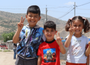 Four Syrian children stand together smiling