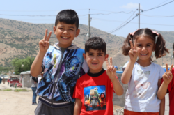 Four Syrian children stand together smiling