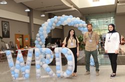 three peace winds staff members stand next to blue and white balloons spelling out "WRD"