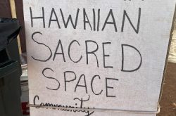 White sign with black handwriting that reads "Honokowai Pu'uhonua Hawaiian Sacred Space. Community Helping Community"