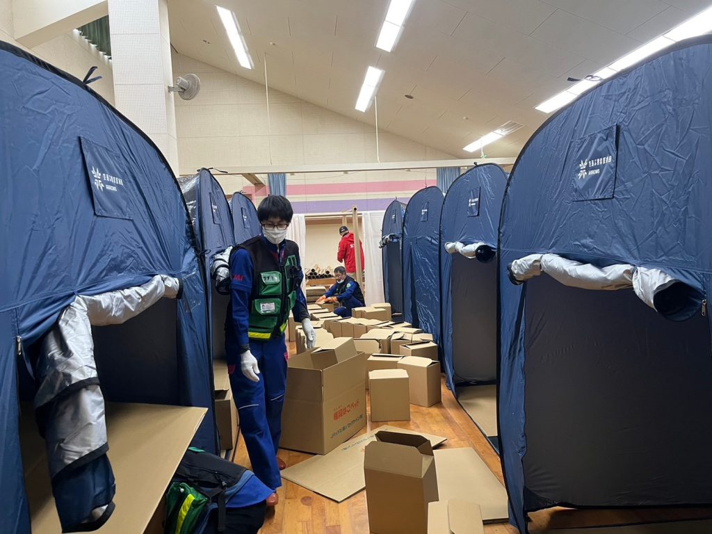 Two rows of blue tents and cardboard boxes of supplies