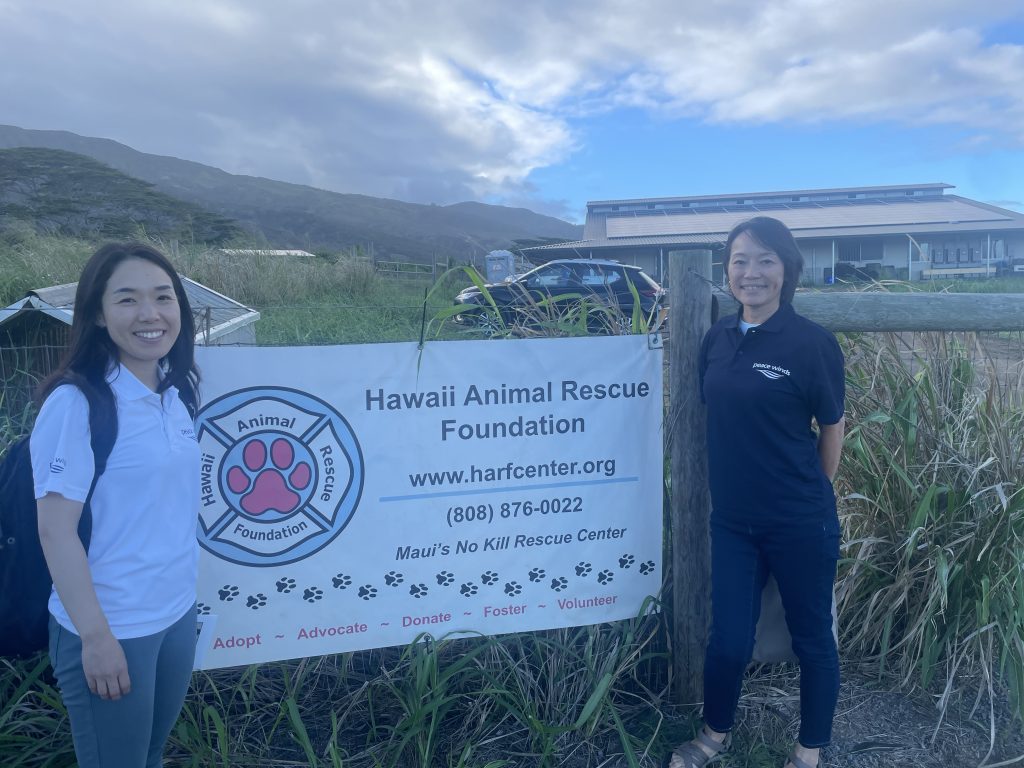 Two Peace Winds staff members stand outside next to a "Hawaii Animal Rescue Foundation" sign
