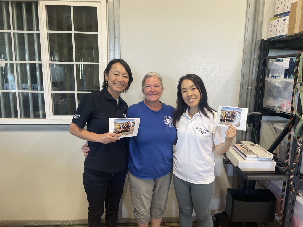 Two Peace Winds staff members pose with a shelter staff member wearing a blue t shirt