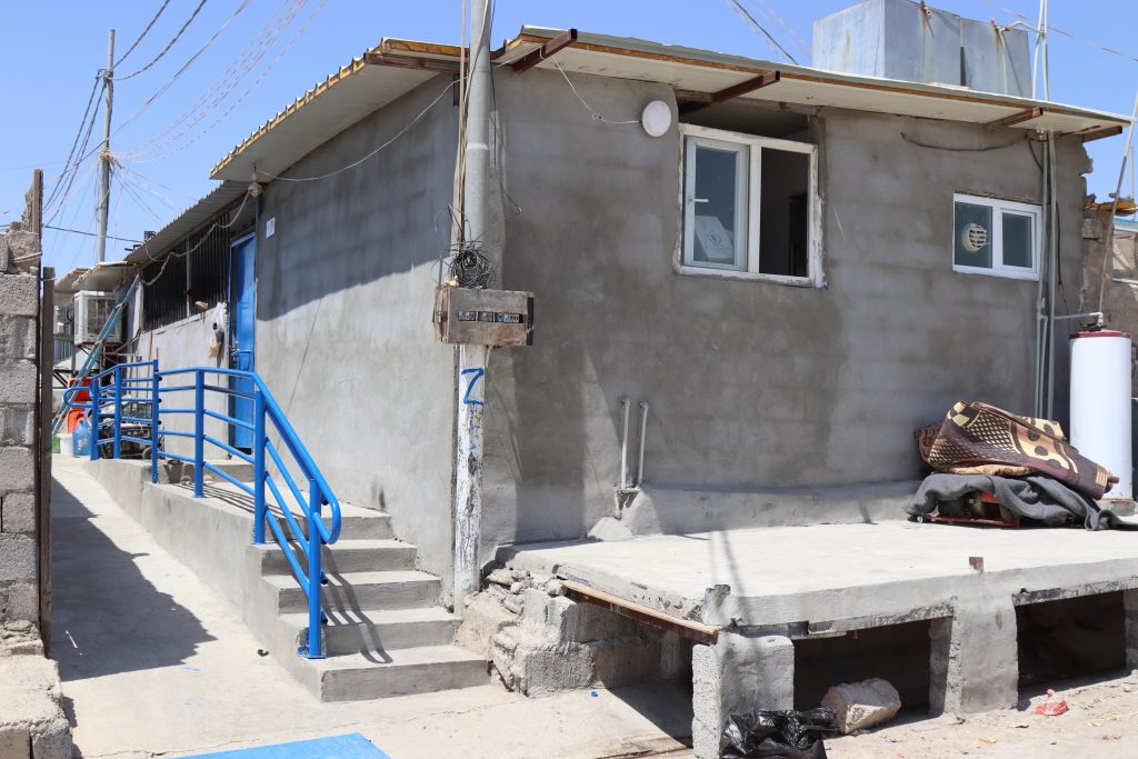 Cinderblock shelter with a new concrete ramp, stairs, and a blue handrail