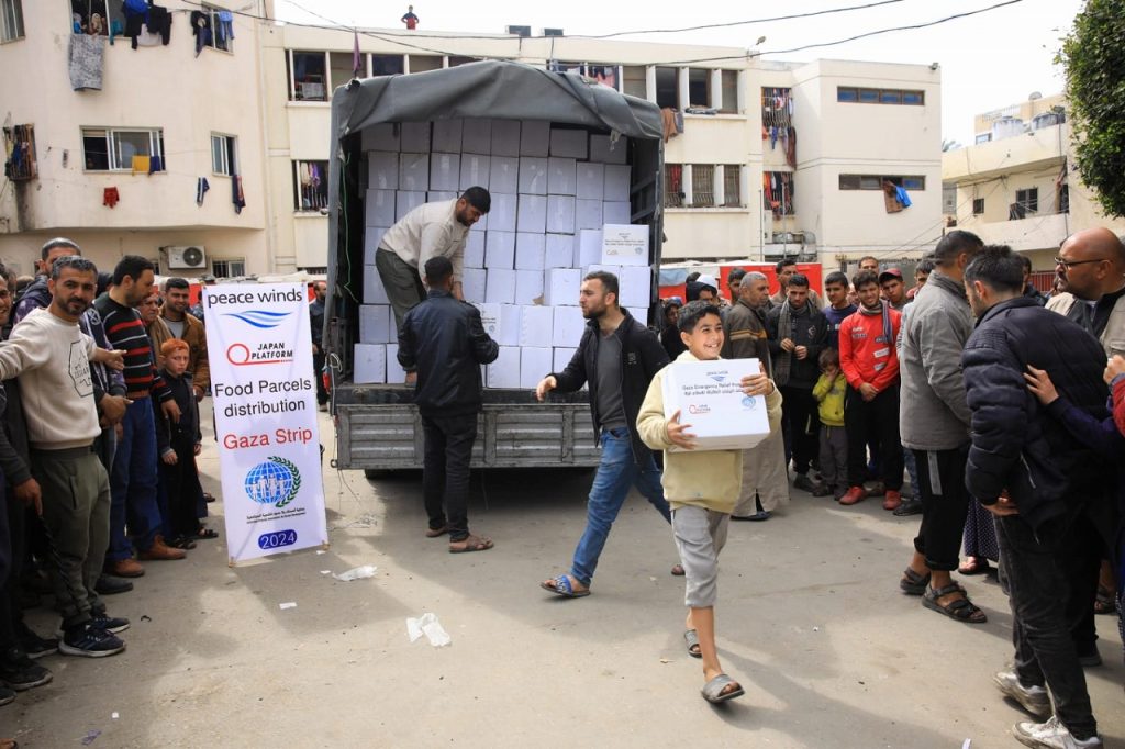 People unload white cardboard boxes from a truck
