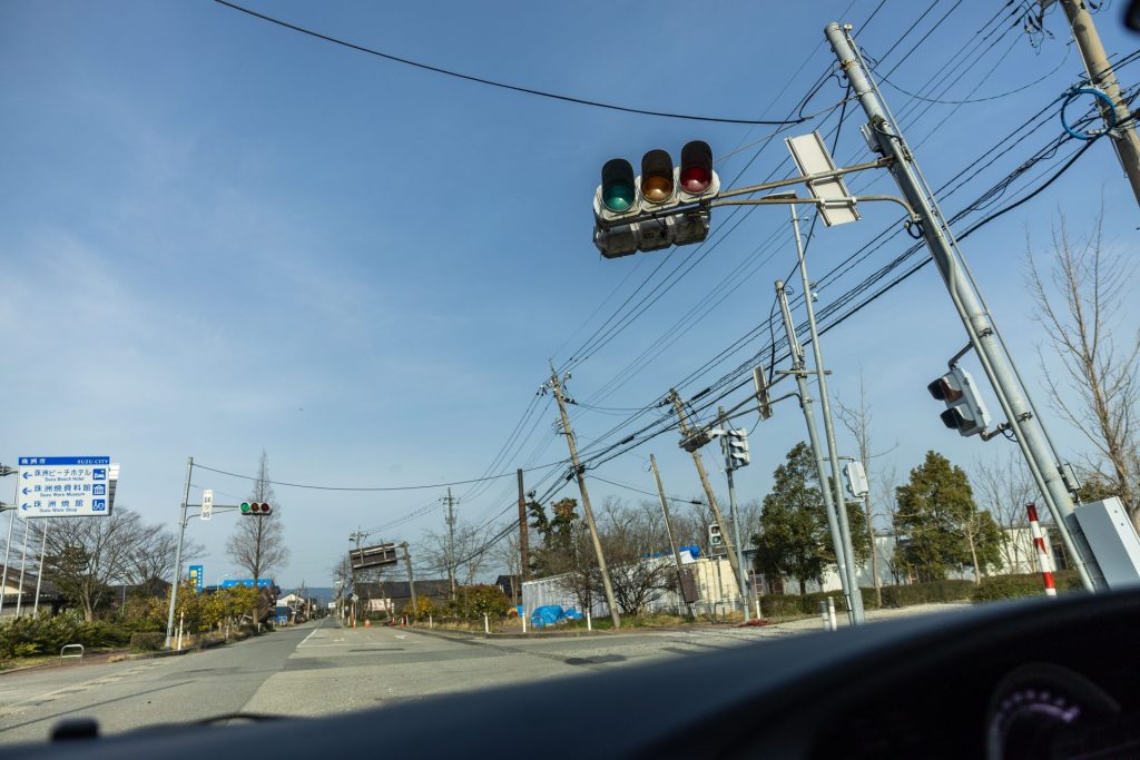 Traffic lights alongside a road stick up at an angle