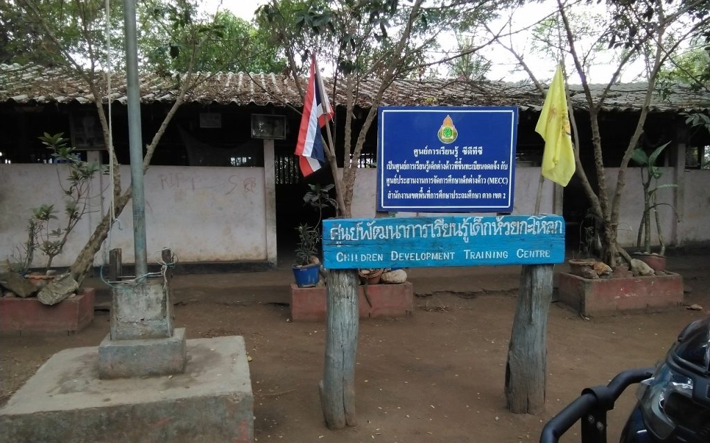 Small one story building with a blue sign out front that says "Children Development Training Center" with additional text in Thai