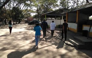 Outdoor view of a simple, single story building with people walking next to it