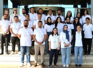 Group of roughly 30 Peace Winds staff members wearing white Peace Winds polo shirts stands on steps for a group photo