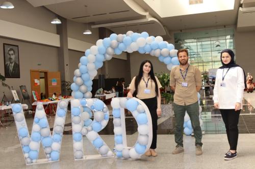 three peace winds staff members stand next to blue and white balloons spelling out "WRD"